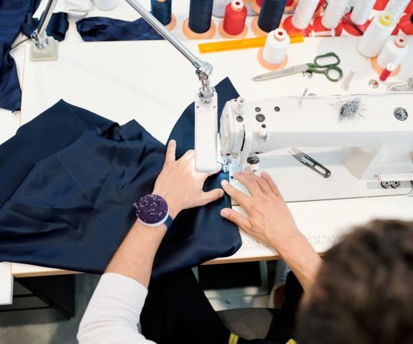 hands-of-young-man-by-sewing-machine-working-over-one-of-orders-of-clients.jpg
